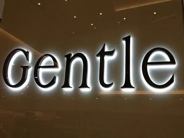 Warm white backlit logo letters on luxury retail storefront