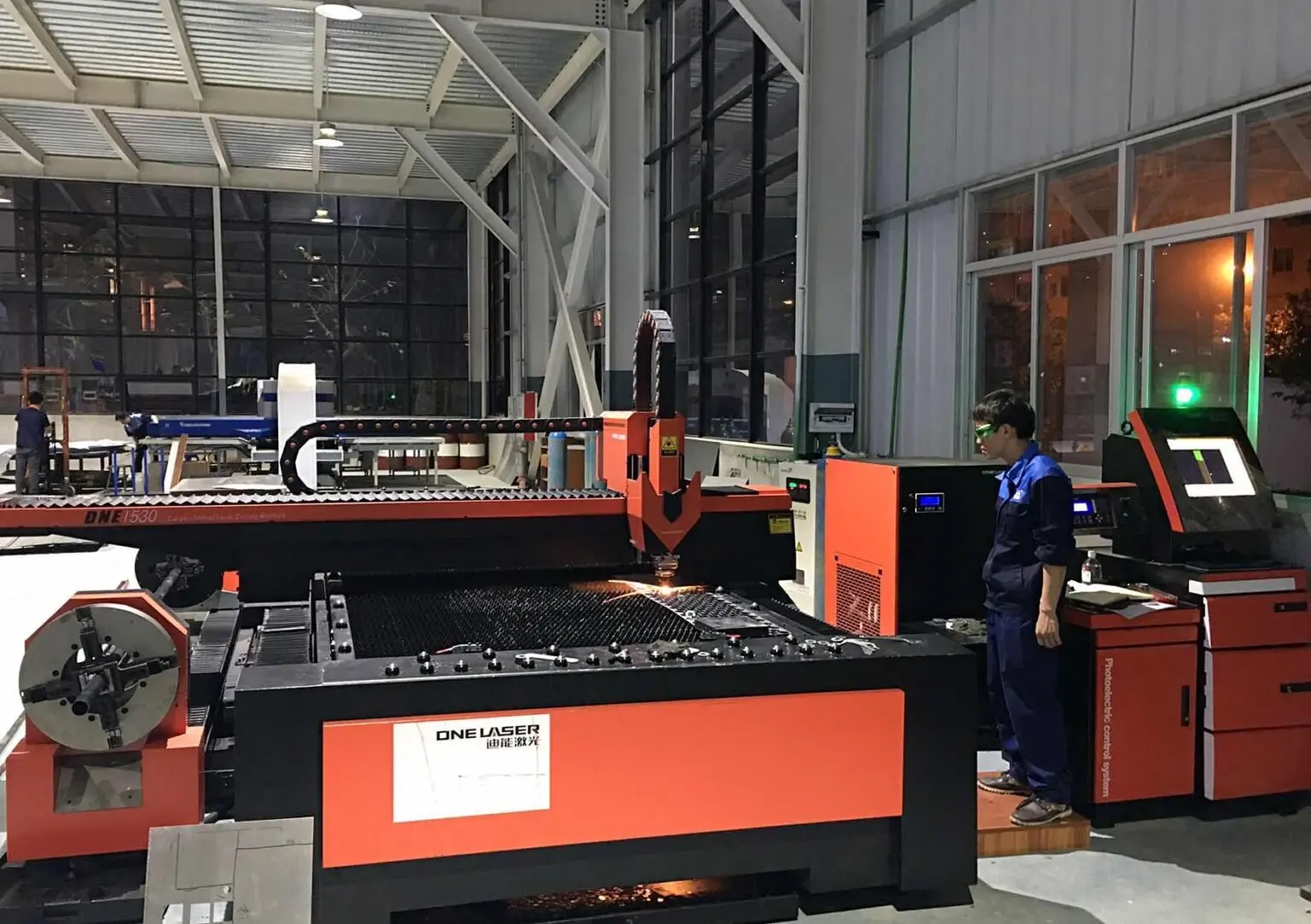 Operator beside a laser cutting machine processing sheet material in the workshop