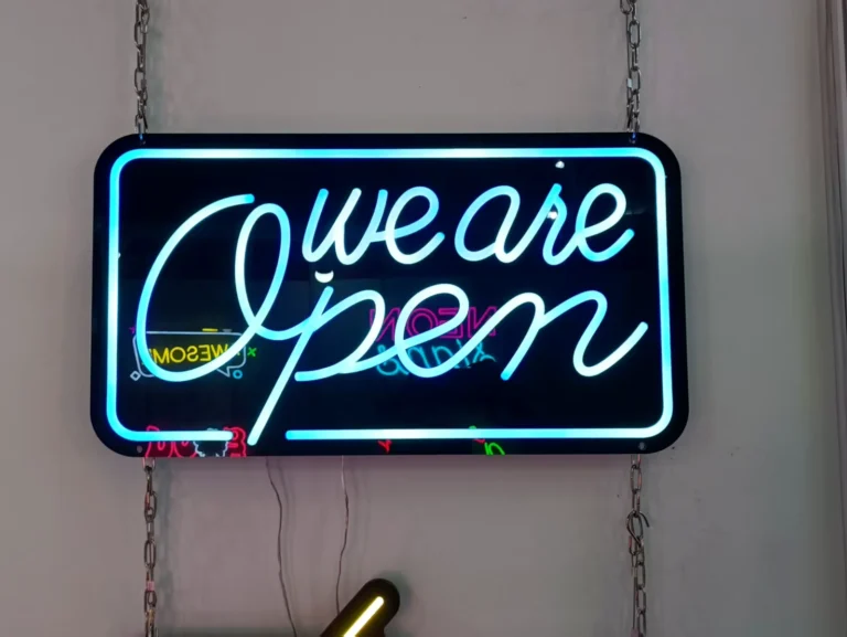 Cyan script and a rectangular illuminated border on a dark hanging sign panel.