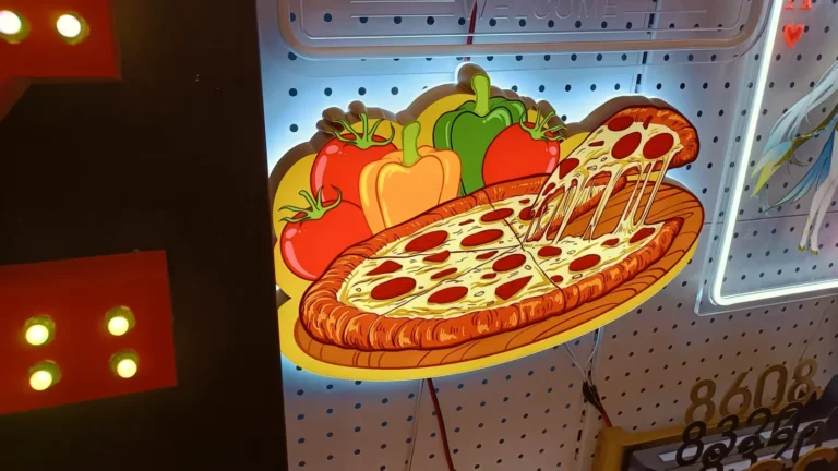 A projecting pizza-shaped illuminated sign with a colorful printed face.
