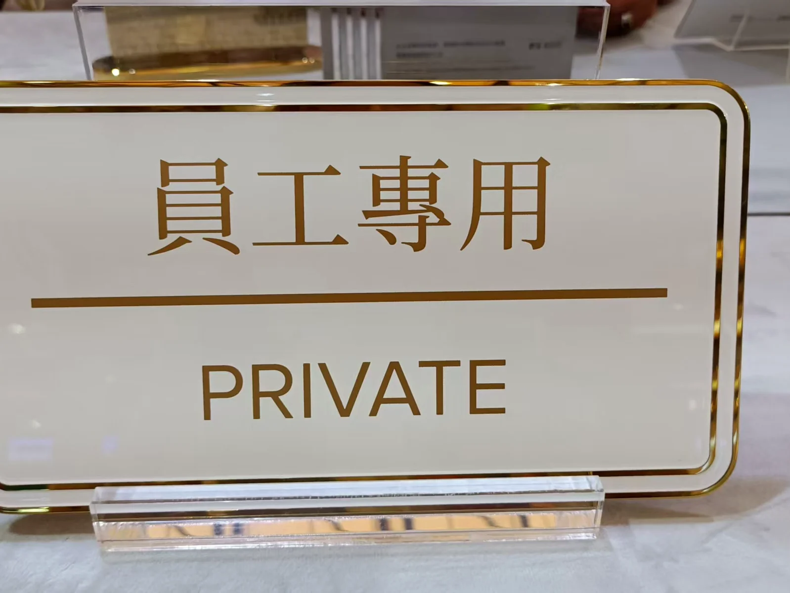 White and gold PRIVATE staff-only identification sign displayed on a clear stand