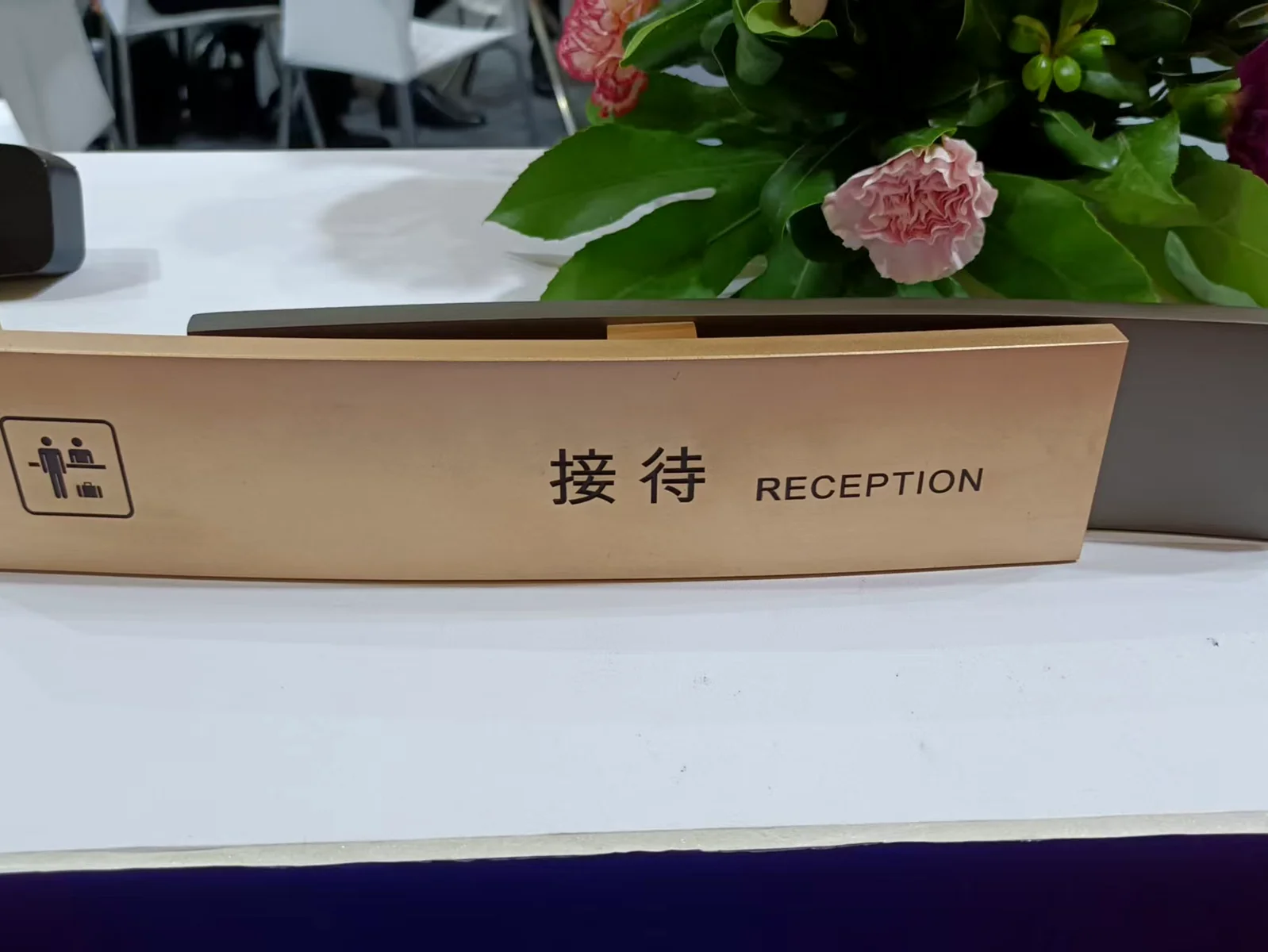A curved metal reception counter sign with Chinese text and the word RECEPTION.