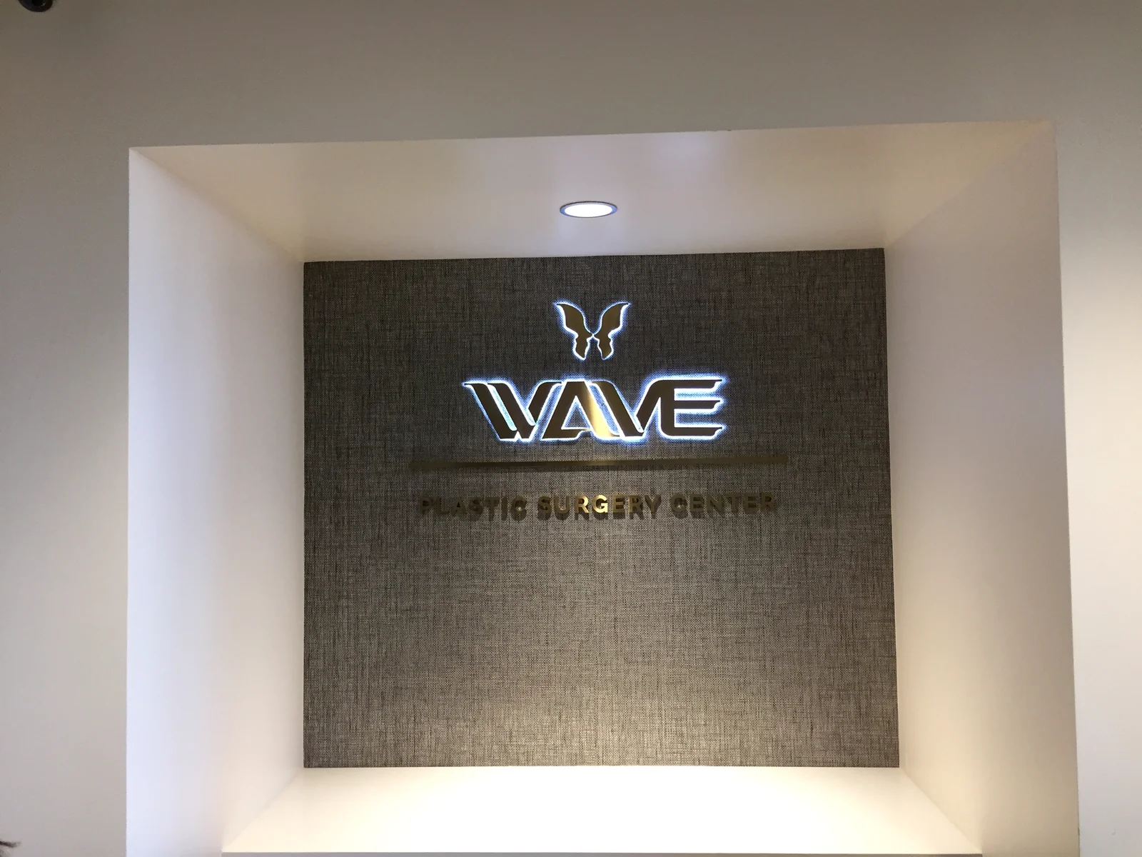 Illuminated WAVE logo and dimensional lettering on a textured reception wall