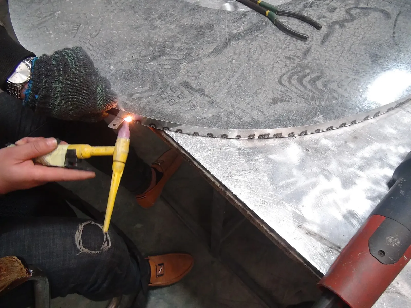 Worker joining the seam of a shaped metal sign component