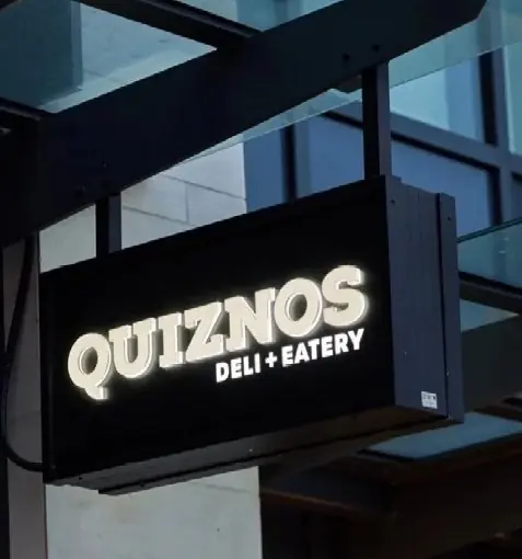 Illuminated double-sided blade sign cabinet installed on a commercial storefront