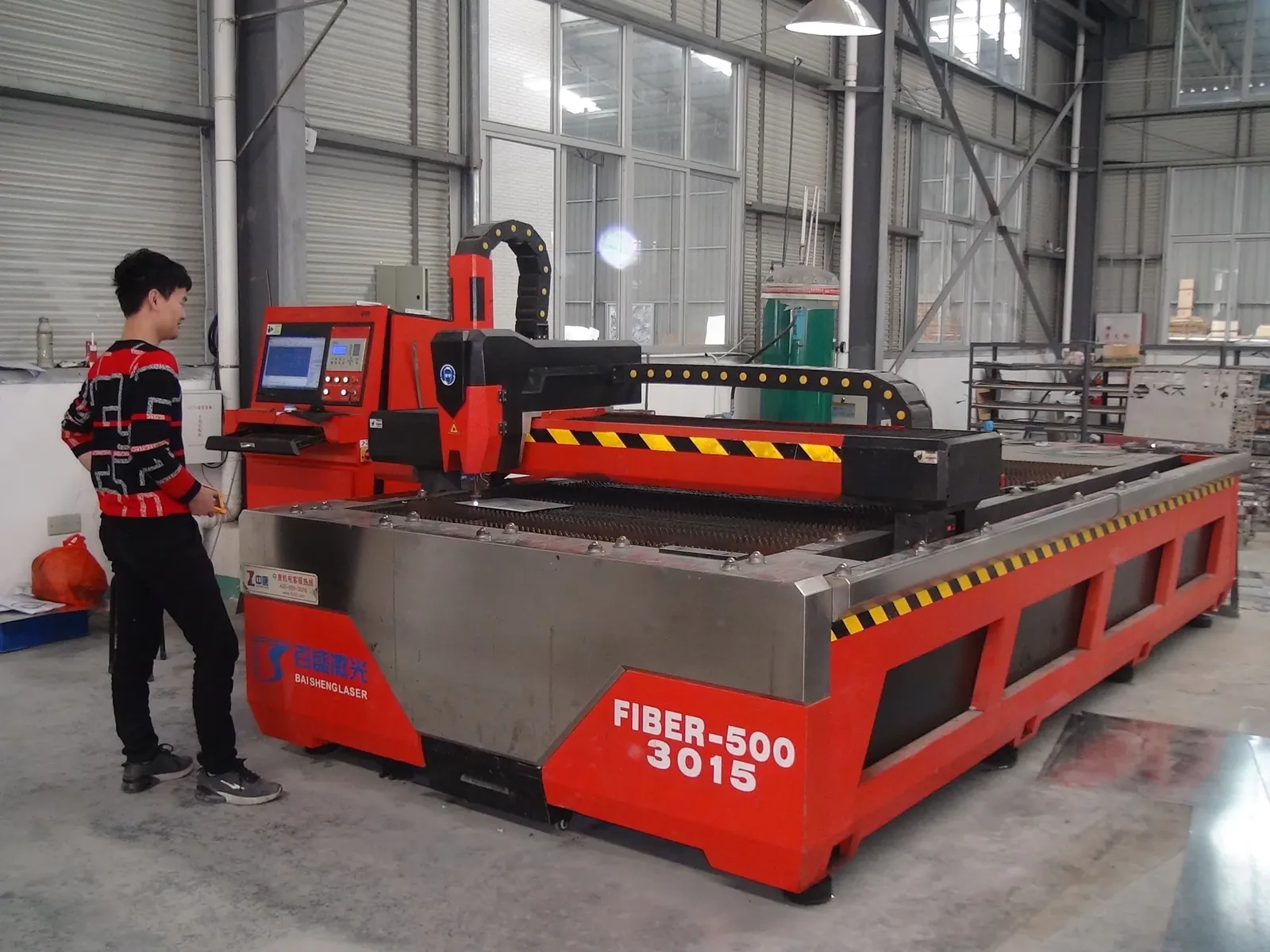 Operator beside a fiber laser cutting machine for metal sign components