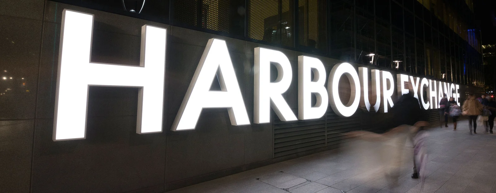 Large illuminated building identification letters along a commercial pedestrian frontage