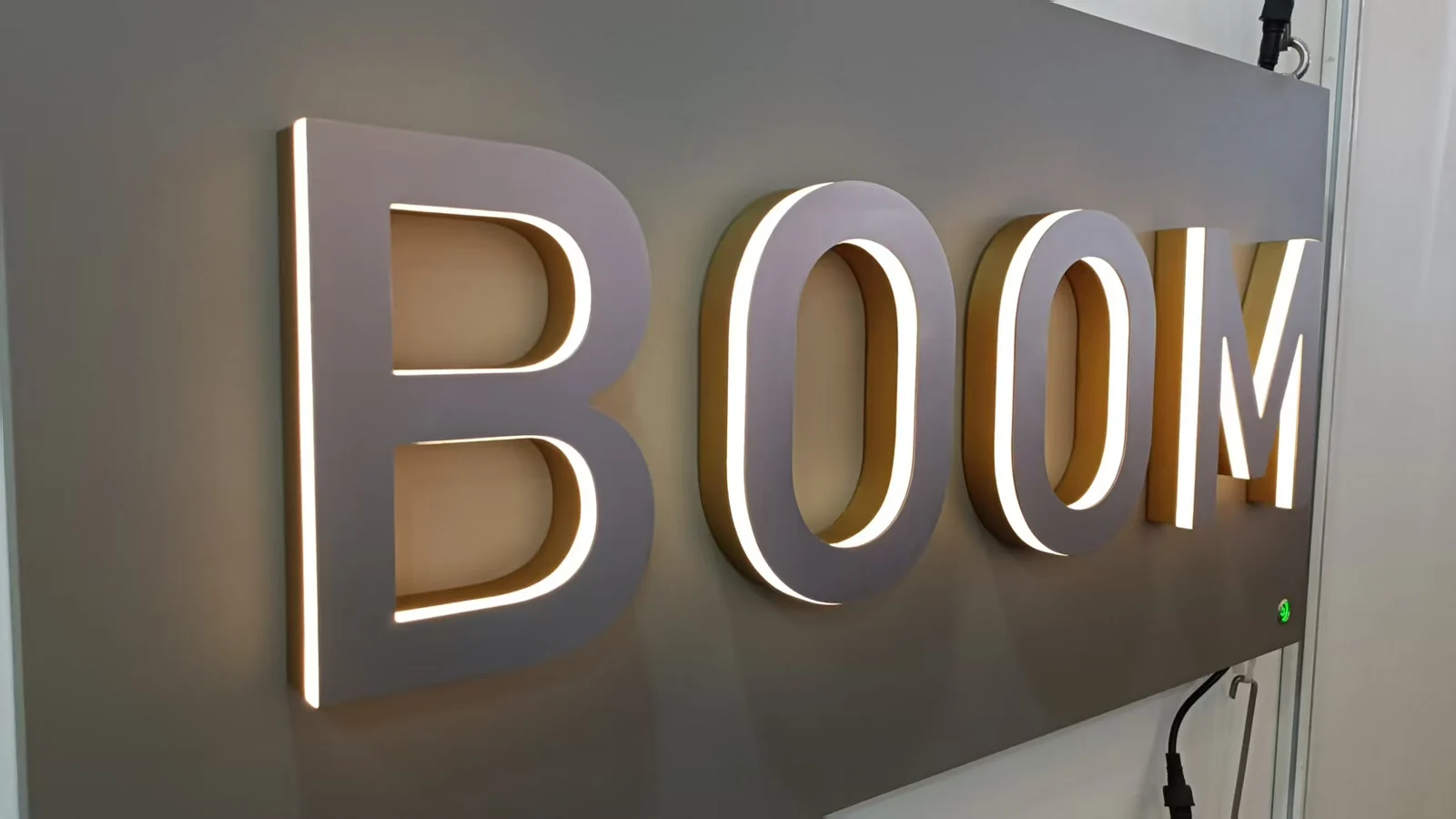 Dimensional BOOM letters with light visible around their edges on a sample panel.
