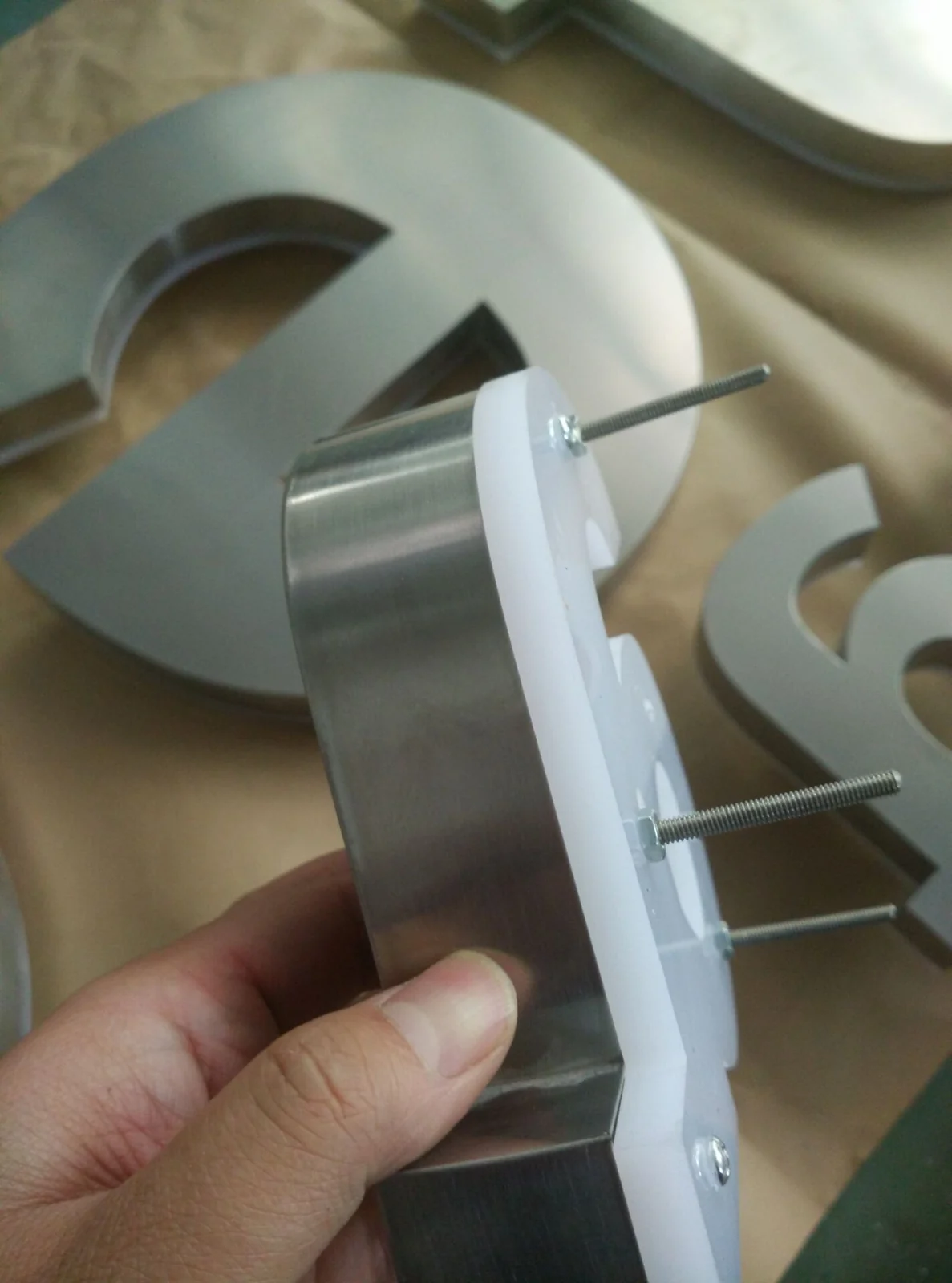 Rear fixing studs projecting from the backing of a metal channel letter