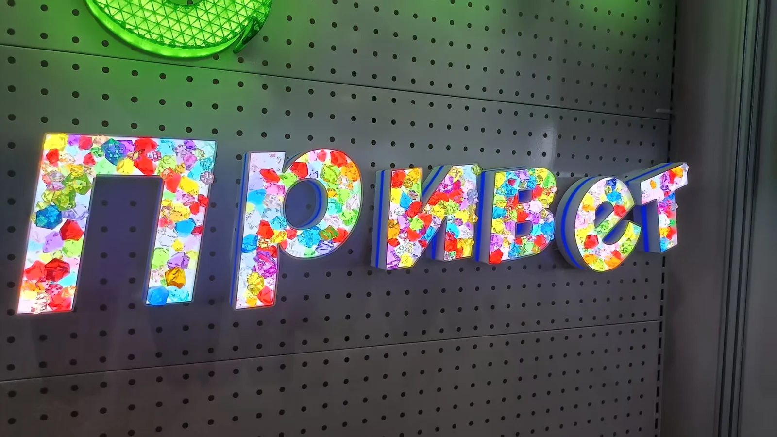 Dimensional letters with multicolored patterned faces on a perforated display panel.