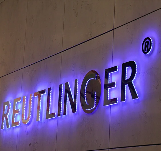 Metallic wall letters with violet-blue light around their edges.