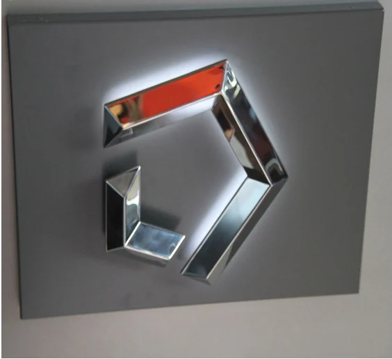 A wall-mounted angular logo with reflective sides and a red inset section.