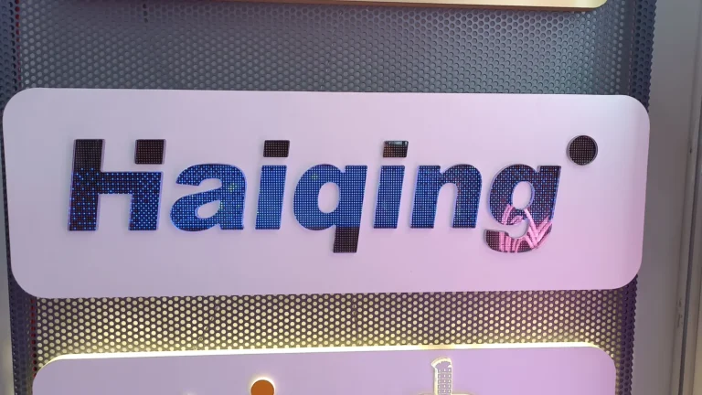 A rectangular white logo panel with blue lettering displayed against a perforated backing.