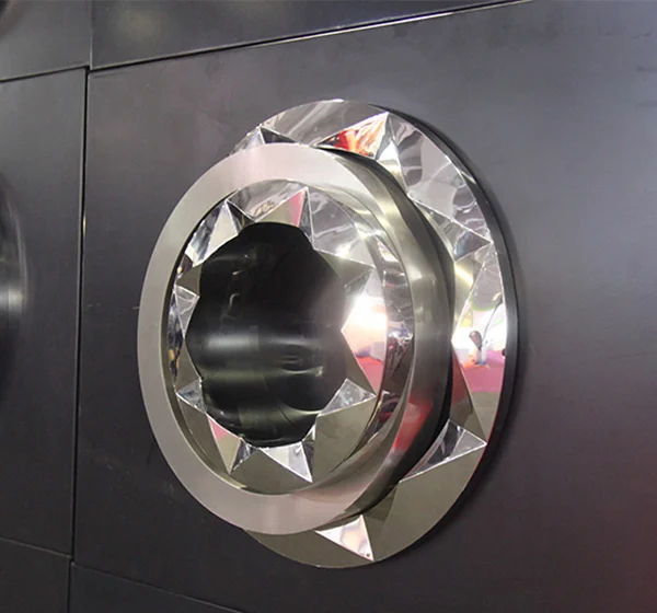 A faceted reflective circular logo with a recessed center mounted on a wall.