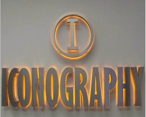 A round monogram above dimensional lettering with warm light on the surrounding wall.
