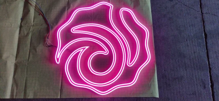 A pink illuminated line-art outline with visible wires on a gridded work surface.