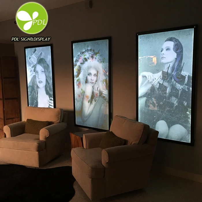 Three illuminated portrait poster displays mounted on an interior wall.
