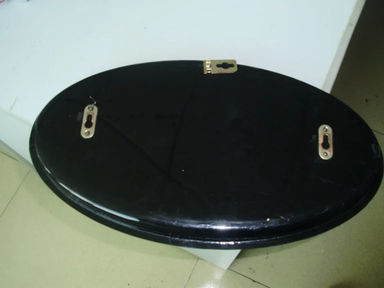 Rear of an oval black sign cabinet showing three attached mounting fittings.