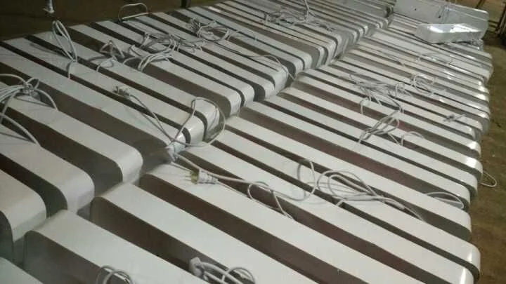 Repeated curved sign cabinet components arranged in rows on a workshop floor.