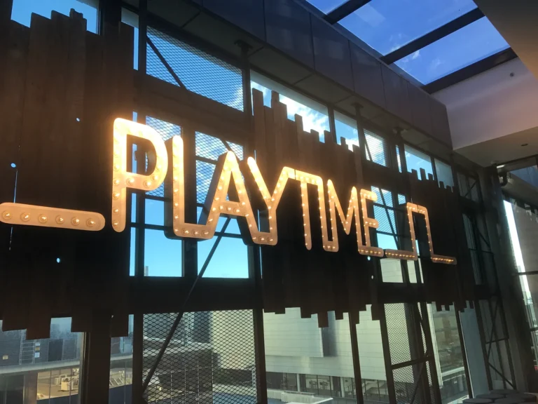 A PLAYTIME marquee letter set mounted behind glass in a commercial interior.