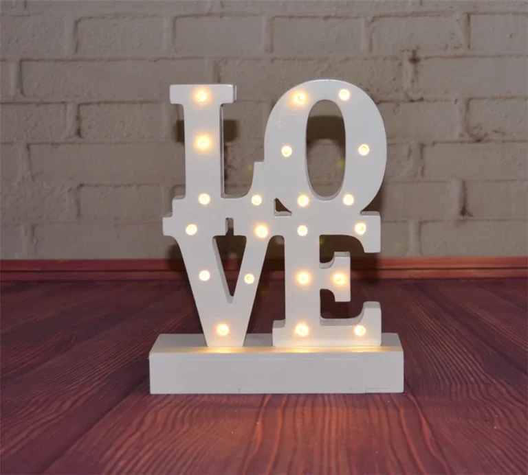 Small white LOVE letters arranged in two rows on a base, with illuminated bulbs.