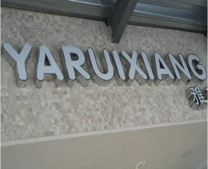 Silver-colored YARUIXIANG lettering and smaller characters mounted on a stone-textured wall.