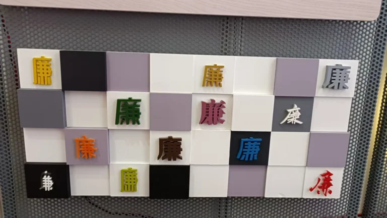 Small colored letter samples arranged across a checkerboard of light and dark panels.