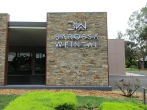 Silver-colored logo and BAROSSA WEINTAL lettering installed on a stone entrance wall.