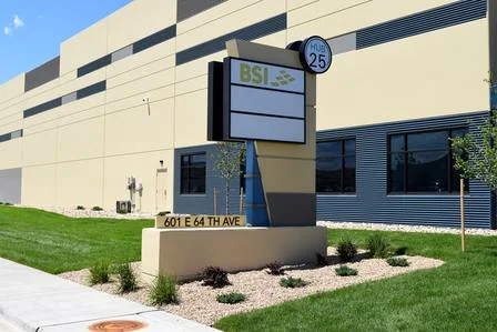 Freestanding BSI cabinet sign with stacked panels and an address base outside a commercial building