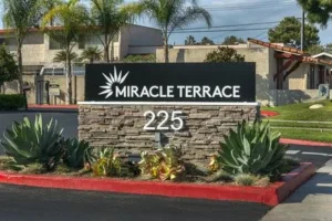 Low monument sign with a stone base, address numbers and landscaped surroundings.