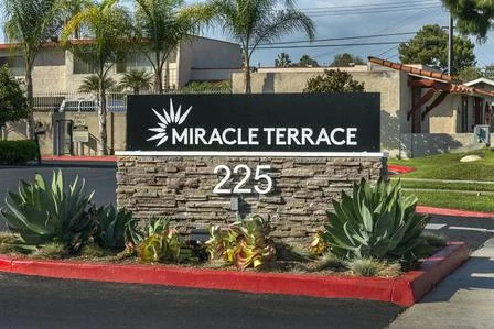 MIRACLE TERRACE entrance monument with address 225 on a stone base beside landscaping