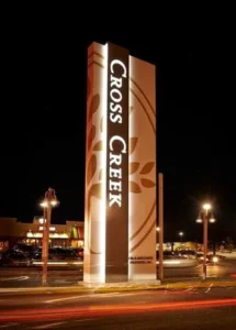 Tall illuminated pylon sign photographed at night in a commercial parking area.